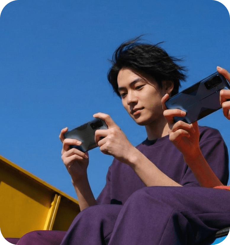 man and woman sitting on top of a building, looking at phones